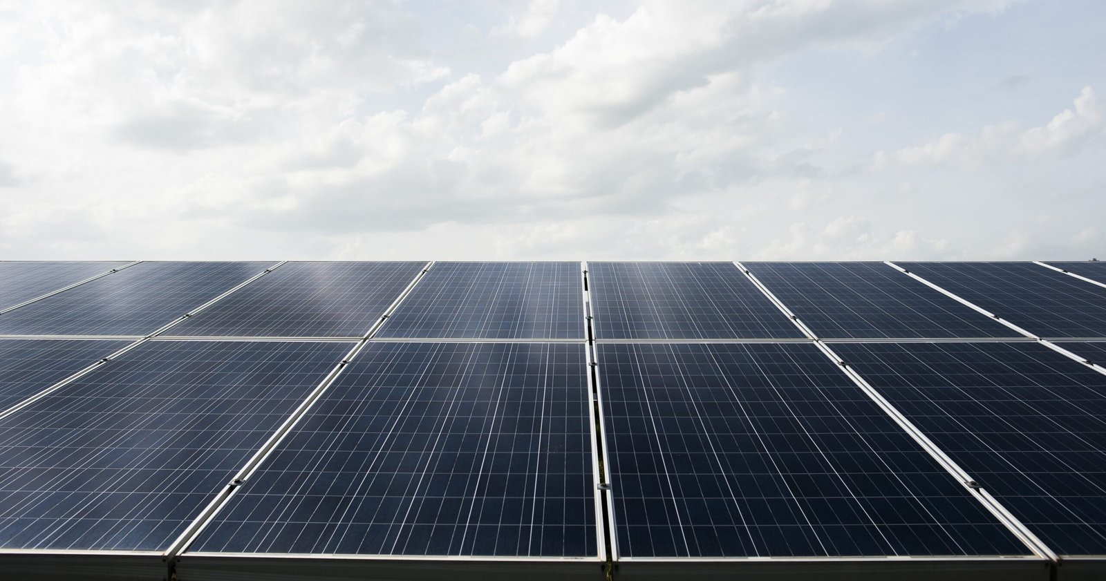 Large solar panel farm under a bright sky, representing sustainable energy generation from sunlight.