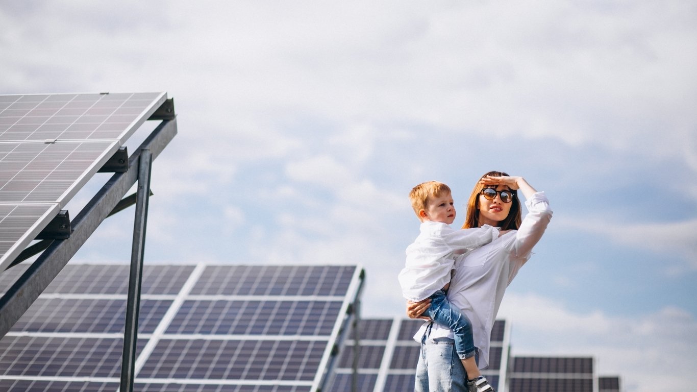 Happy family standing in front of their house with rooftop solar panels